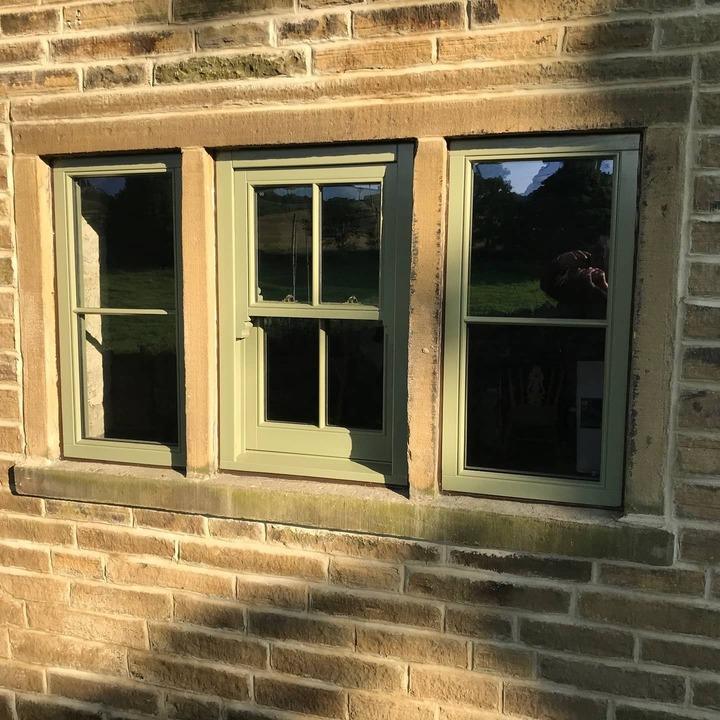 Sage green timber sash window set into a stone wall