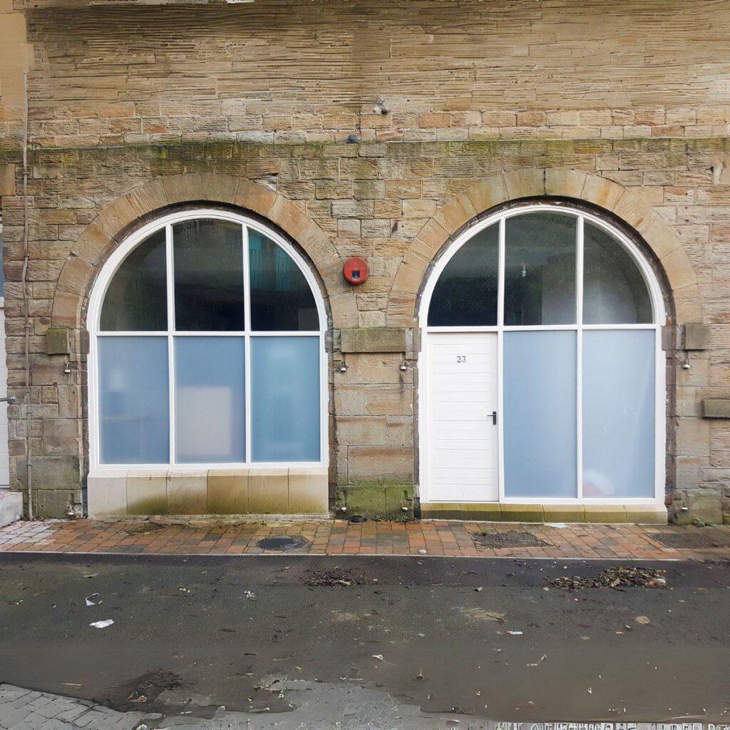 Pair of tall arched timber windows in a stone elevation