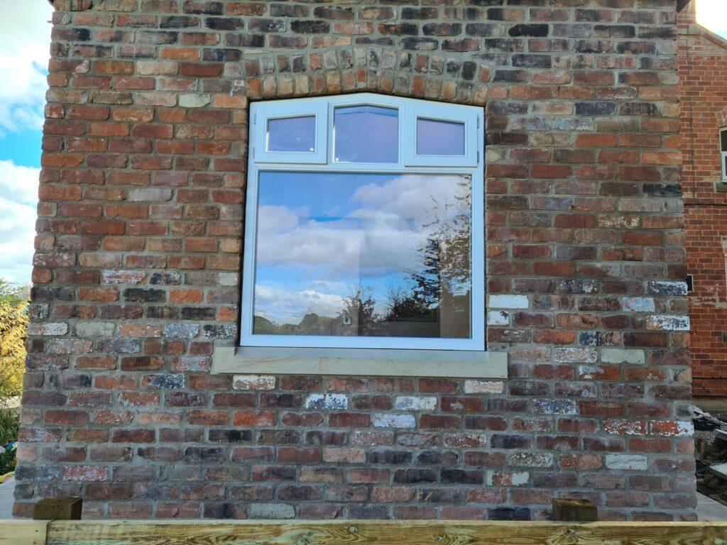 Robust timber casement window set into brickwork at Hunsingore